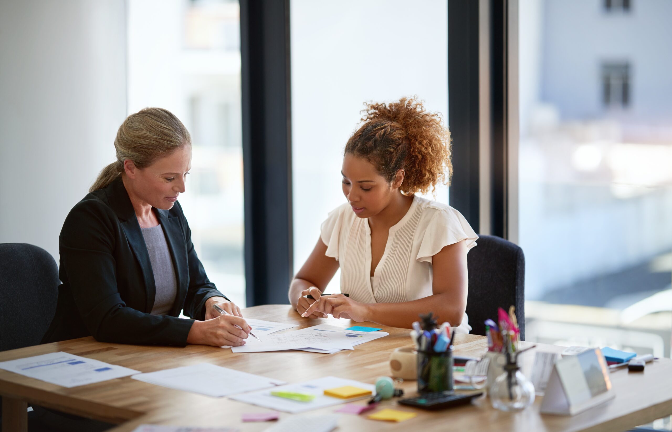 two women sitting at a desk reviewing paperwork
