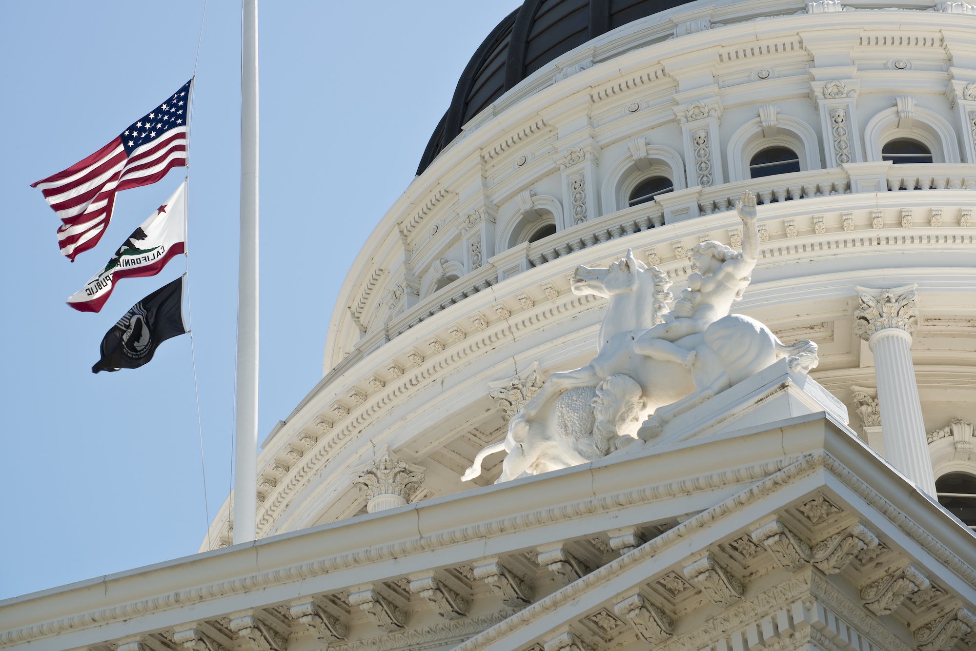 exterior of California state capital with the American flag and California flag.